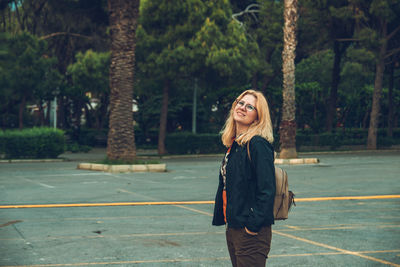 Full length portrait of woman standing against trees