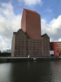 Low angle view of building by river against sky