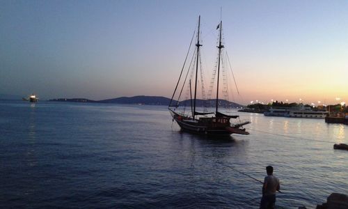 Boats sailing in sea at sunset