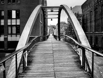 Footbridge amidst buildings against sky