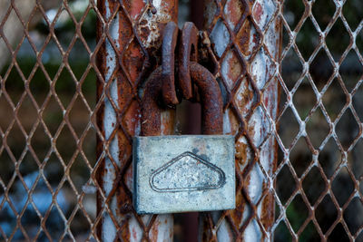 Close-up of rusty padlock on fence