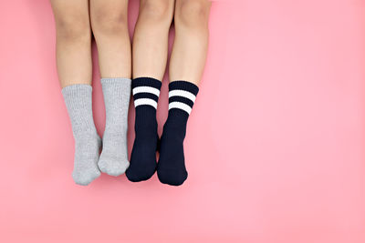 Low section of children wearing socks while resting over colored background