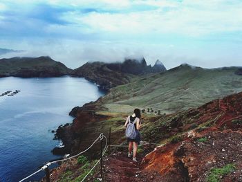 Rear view of woman standing on mountain against sky