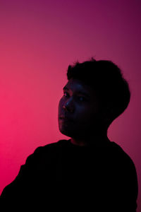 Portrait of boy looking away against pink background