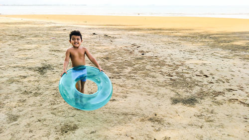 Portrait of boy with inflatable raft at beach