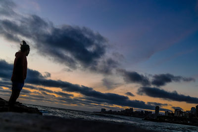 Man standing on beach against sky during sunset