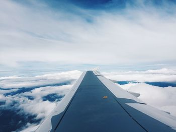 Airplane wing over clouds against sky