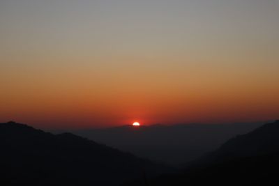 Scenic view of silhouette mountains against orange sky