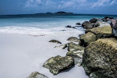 Scenic view of rocks on beach against sky