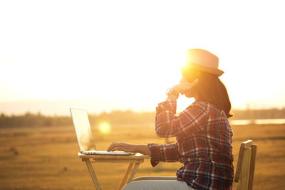 Man using smart phone against sky during sunset