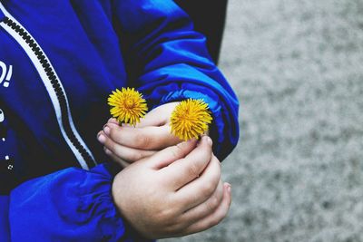 Midsection of child holding flower while standing outdoors