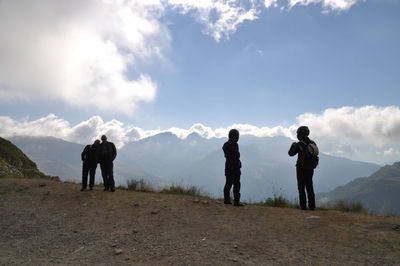 Rear view of woman standing on mountain against cloudy sky