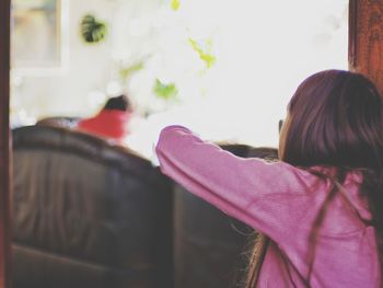 Side view of young woman sitting on sofa at home