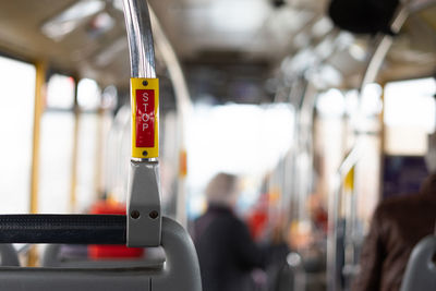 Bus interior in circulation with the stop button in the foreground on a blurred background.