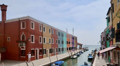 Buildings by canal against sky in city