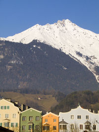 Houses on snowcapped mountains against clear sky