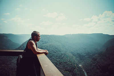 Side view of young man looking at mountains on a landscape