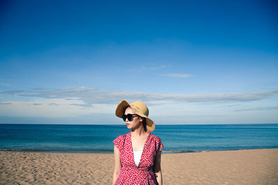 Young woman wearing sunglasses standing on beach