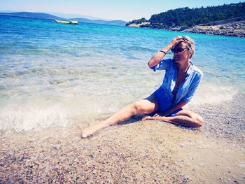 Full length of woman sitting at beach