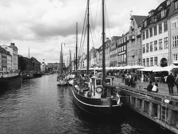 Boats moored at harbor against sky in city