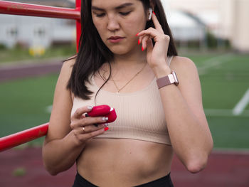 Midsection of woman holding smart phone while standing outdoors