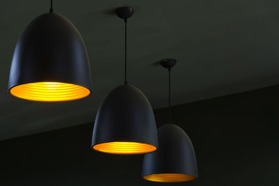 Low angle view of illuminated pendant lights hanging from ceiling