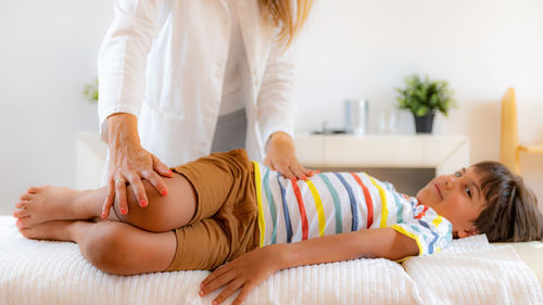 Pediatric doctor doing medical exam with boy on bed