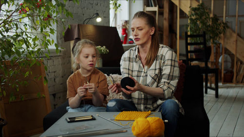 Mother teaching crocheting to daughter