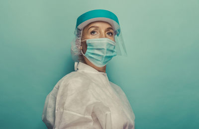 Female doctor wearing mask against blue background