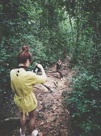 Rear view of woman photographing in forest