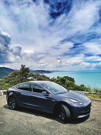 Car on road by sea against sky