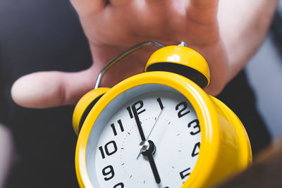 Midsection of man holding yellow clock