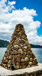 Stack of stones by sea against sky