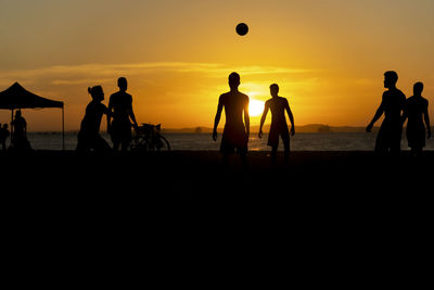  young people playing beach soccer during sunset at ribeira beach in salvador, bahia, brazil.