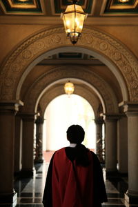 Rear view of man standing in illuminated building