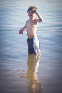 Full length of shirtless boy standing in lake