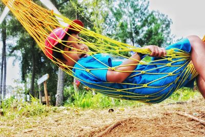 Side view of boy relaxing on hammock against trees
