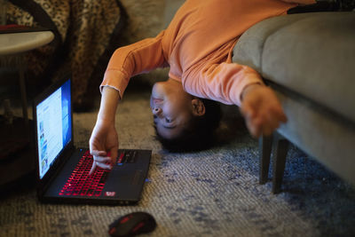 A 12-year old boy in an unusual body position uses a laptop computer