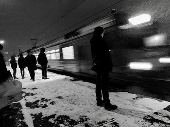 Silhouette people walking on illuminated road at night during winter