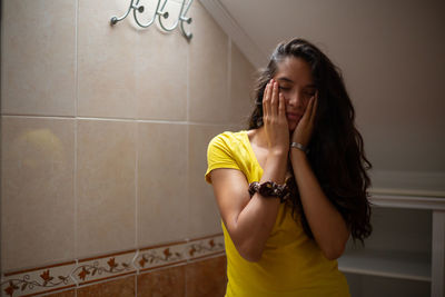 Portrait of young woman standing against wall