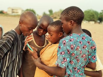 Teenage friends using mobile phone while standing at field