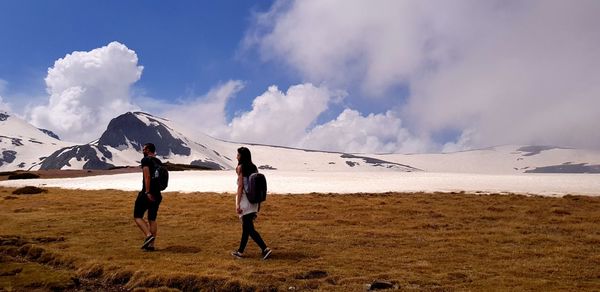 Rear view of men on snowcapped mountain against sky