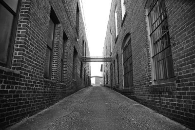 Empty footpath amidst buildings against clear sky