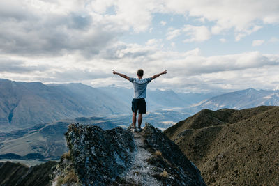 Full length of men standing on mountain against sky