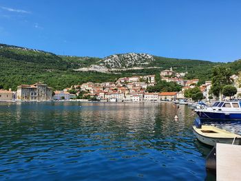 Scenic view of lake by buildings against clear blue sky