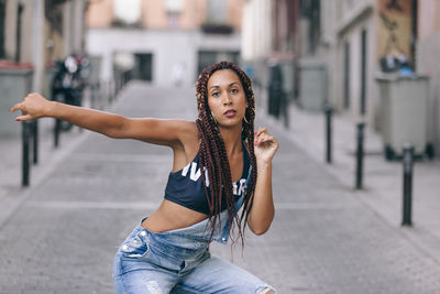 Portrait of woman dancing on street against building