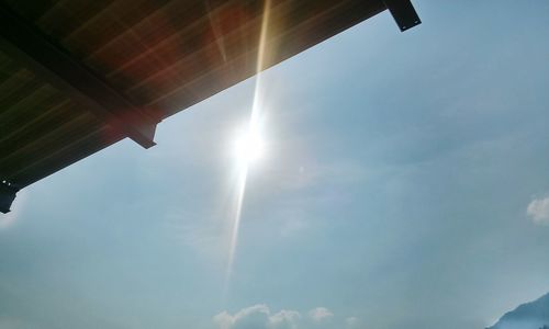 Low angle view of sun shining through clouds