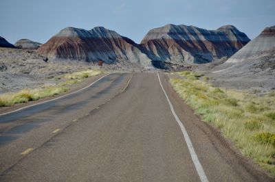 Road by mountains against sky