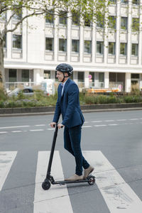 Young businessman riding e-scooter in the city