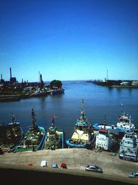 Boats in harbor against clear blue sky